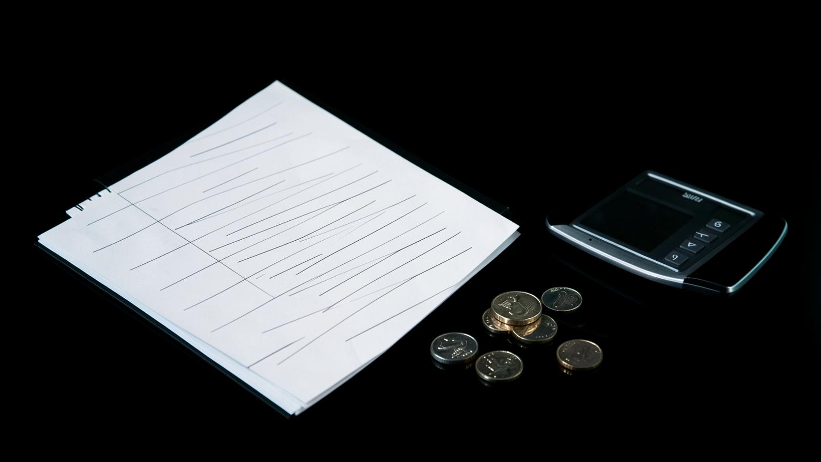 Ledger, calculator and UAE dirham coins on a black desk